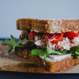 Tuna salad sandwich with lettuce, tomato, and mayonnaise on whole grain bread