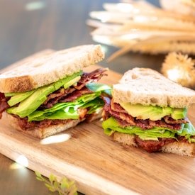 Fresh sandwich with crispy bacon, leafy greens, and sliced avocado on rustic bread